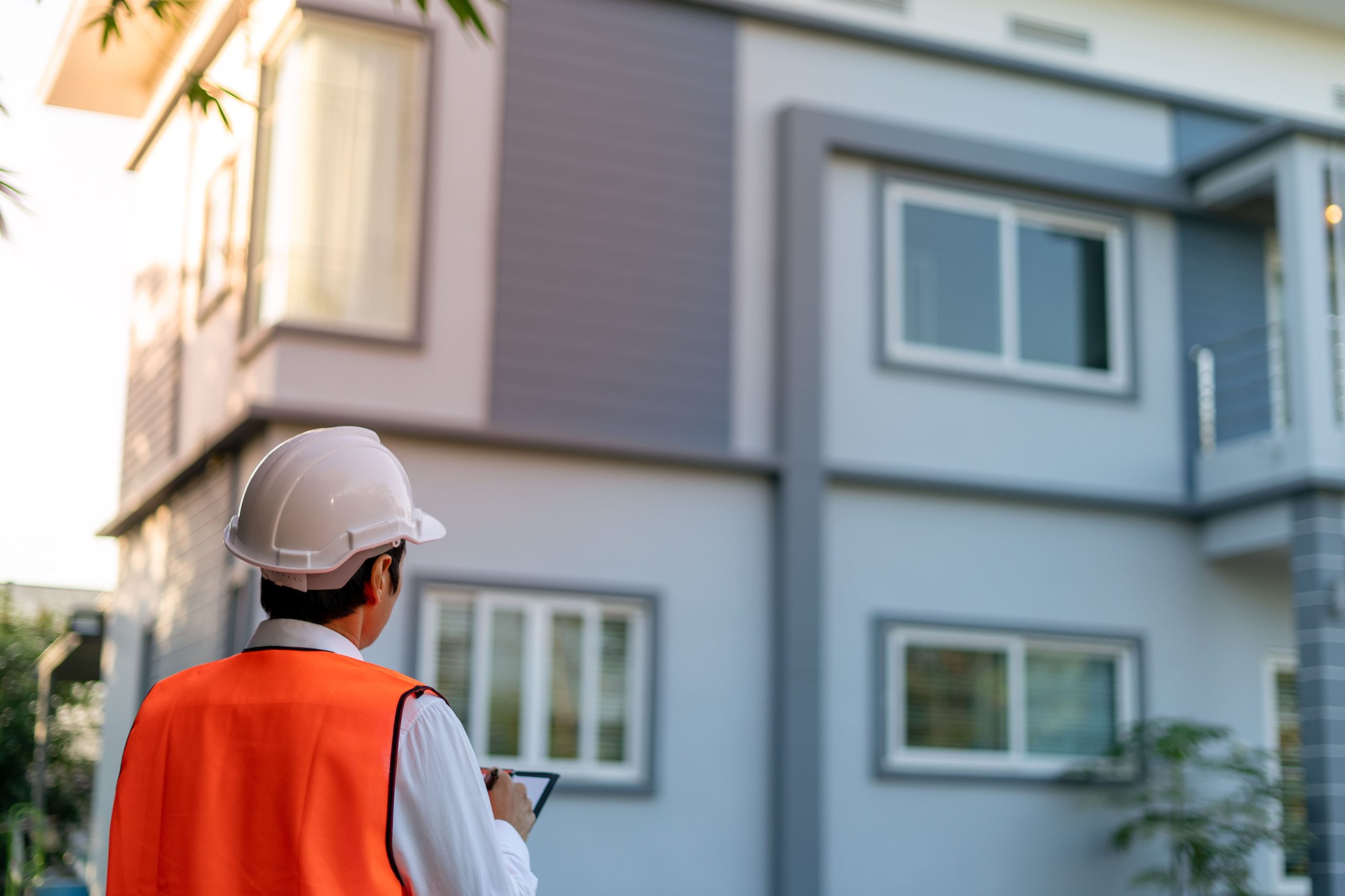 inspector wearing a hi-vis jacket outside of a house